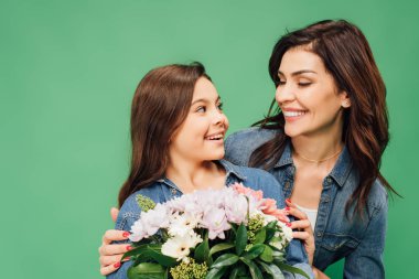 güzel anne kucaklama kız yeşil izole çiçek buketi ile