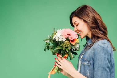 Holding ve yeşil izole çiçek buketi koklama gülümseyen kadın
