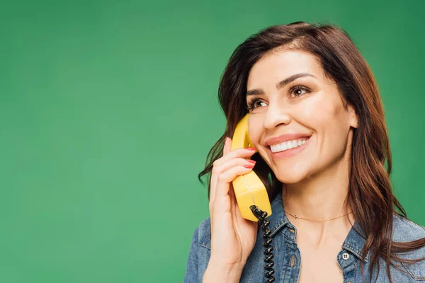smiling beautiful woman talking on vintage telephone isolated on green