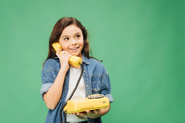 cute smiling child talking on vintage telephone isolated on green