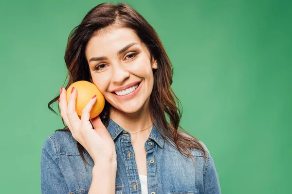 Smiling Woman Denim Holding Orange Looking Camera Isolated Green — Stock Photo, Image