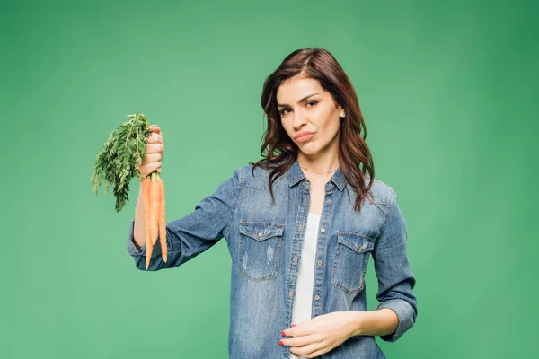 Skeptical Woman Holding Carrots Looking Camera Isolated Green — Stock Photo, Image