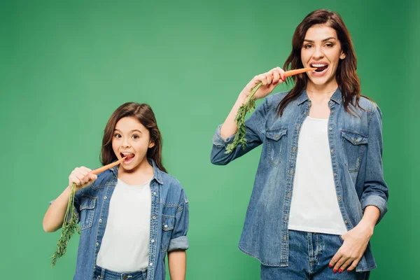 Mother Daughter Eating Carrots Looking Camera Isolated Green — Stock Photo, Image
