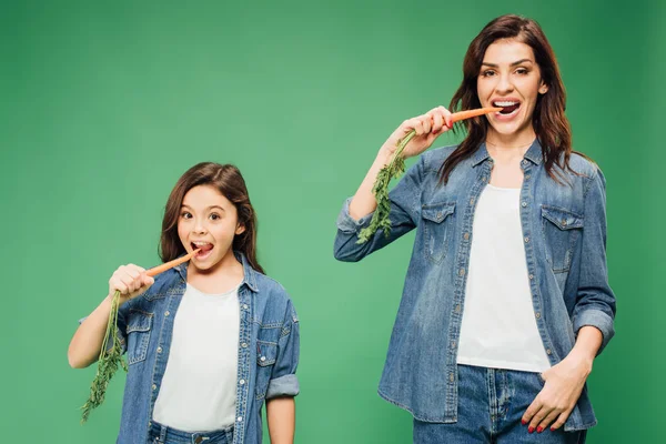 Moeder Dochter Eten Wortelen Kijken Naar Camera Geïsoleerd Groen — Stockfoto