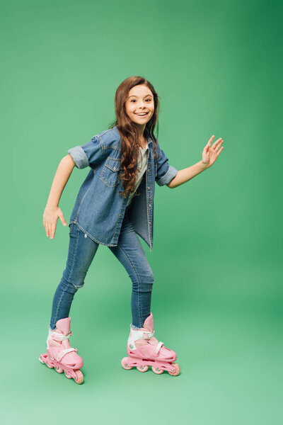 smiling child rollerblading with outstretched hands on green background
