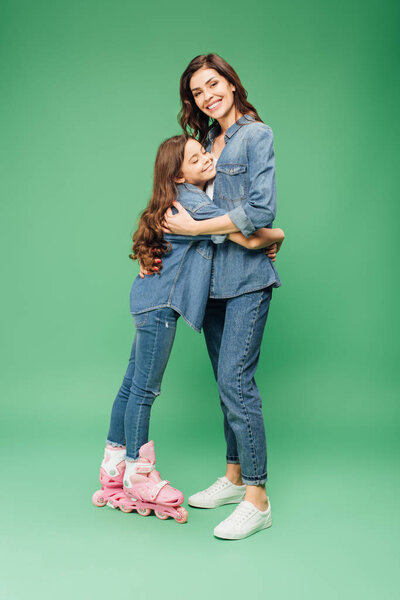daughter in roller blades hugging mother on green background
