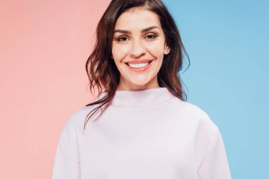 beautiful woman looking at camera and smiling on blue and pink background