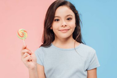çok güzel çocuk şeker mavi ve pembe arka plan üzerinde kameraya bakarken holding