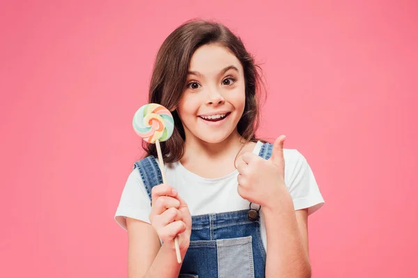 Uśmiechnięte Dziecko Trzymając Lizak Pokazuje Kciuk Białym Tle Różowy — Zdjęcie stockowe