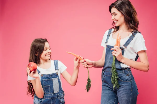 Vrolijke Moeder Wortel Geven Aan Dochter Geïsoleerd Roze — Stockfoto