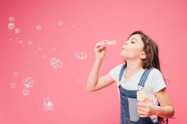 joyful kid blowing soap bubbles isolated isolated on pink