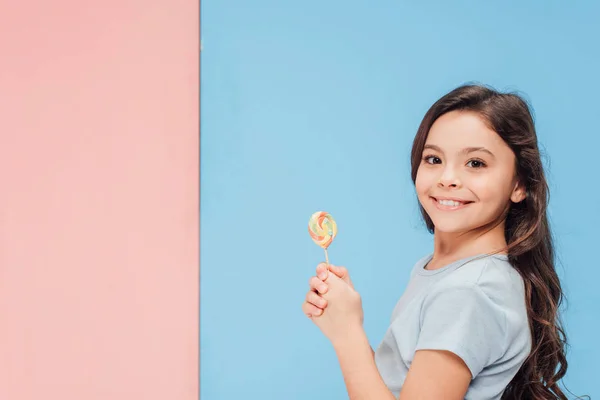 Adorable Child Holding Lollipop Looking Camera Blue Pink Background — Stock Photo, Image