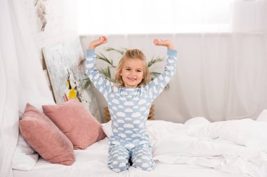 şirin çocuk pijama yatakta elleri havada olan oturan gülümseyen 