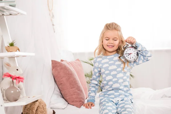 Szczęśliwy Adorable Kid Siedząc Łóżku Zegarem Zamknięte Oczy — Zdjęcie stockowe