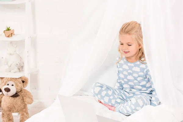Niño Sonriente Sentado Cama Pijama Usando Ordenador Portátil — Foto de Stock
