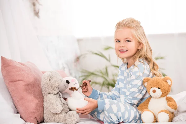 Criança Sorridente Pijama Alimentando Brinquedos Macios Cama — Fotografia de Stock