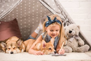 Kızılderili çadırı Galce corgi köpeklerle içinde yatan ve evde not defterinde yazılı sevimli çocuk