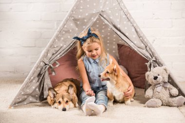 Kızılderili çadırı evde Galce corgi köpek ile oturma sevimli çocuk