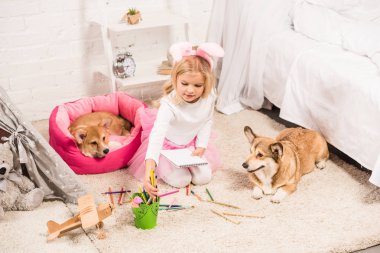 Çocuk Galce corgi köpek evde oturan ve kalem boyama ile çizim tavşan kulaklar kafa bandı