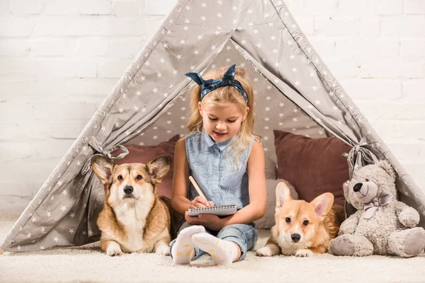 Urocze Dziecko Siedzi Psami Corgi Wigwamie Pisanie Notesie — Zdjęcie stockowe