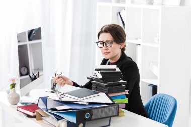 office belgelerinde yığını bakarak bardaklarda üzgün yorgun çekici iş kadını