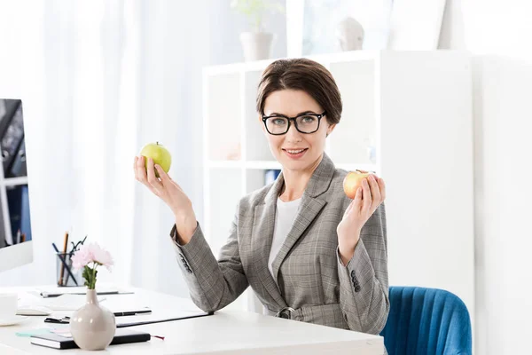 Attrayant Femme Affaires Tenant Des Pommes Regardant Caméra Dans Bureau — Photo