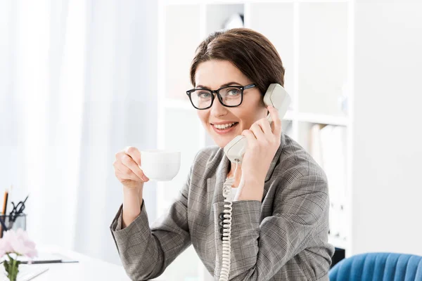Sabit Telefonla Konuşurken Ofiste Kahve Içme Gülümseyen Çekici Kadını — Stok fotoğraf