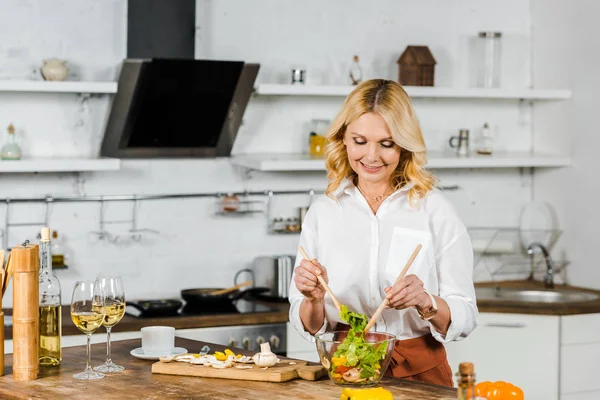 Atractiva Mujer Madura Sonriente Mezclando Ensalada Cocina —  Fotos de Stock