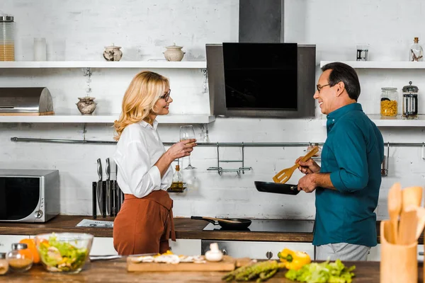 Rijpe Vrouw Houdt Van Glas Wijn Man Koken Het Fornuis — Stockfoto