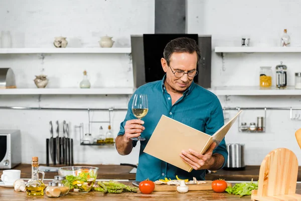 Knappe Volwassen Man Met Glas Wijn Kookboek Keuken — Stockfoto