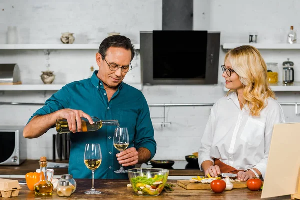 Bonito Maduro Marido Derramando Vinho Copos Esposa Cortando Legumes Cozinha — Fotografia de Stock