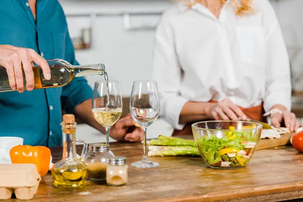 Cropped Image Mature Husband Pouring Wine Glasses Wife Cutting Vegetables — Stock Photo, Image