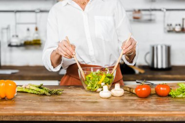Olgun kadın mutfakta cam kase salata karıştırma görüntü kırpılmış