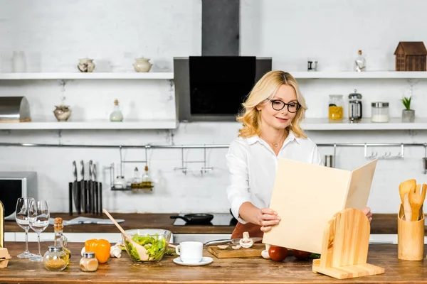 Attraktiv Mogen Kvinna Tar Receptbok För Matlagning Köket — Stockfoto