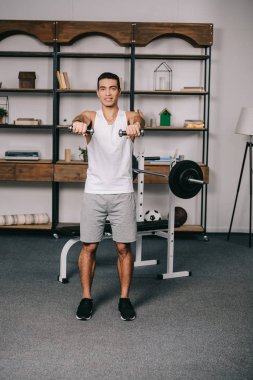 oturma odasında dumbbells ile egzersiz yakışıklı bı ırkçı adam 