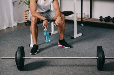 Halter oturan ve spor şişe tutan adamın kırpılmış görünümü 
