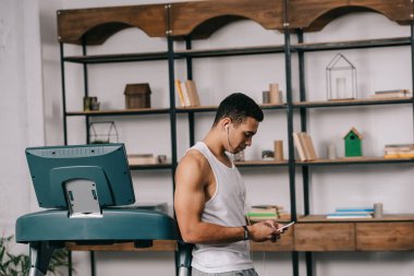 spor içinde ayakta ve smartphone kullanırken kulaklık müzik dinleme kas bı ırkçı adam