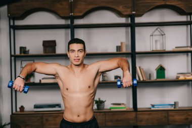 yakışıklı bı ırkçı adam ev jimnastik salonu içinde mavi dumbbells ile egzersiz 