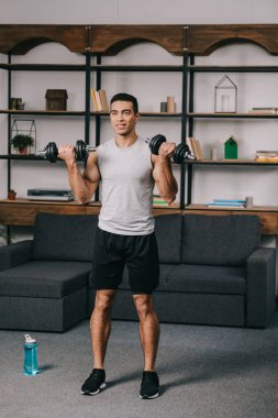 neşeli karışık yarış adam egzersiz oturma odasında dumbbells ile 