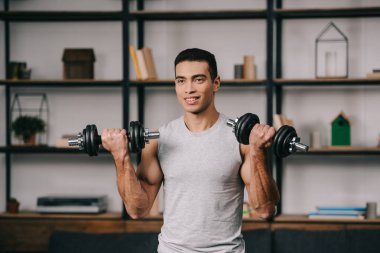 karışık yarış adam egzersiz oturma odasında dumbbells ile gülümseyen 