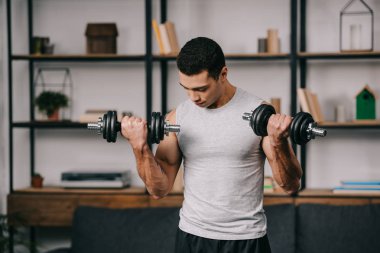 oturma odasında dumbbells ile eğitim güçlü karışık yarış adam 