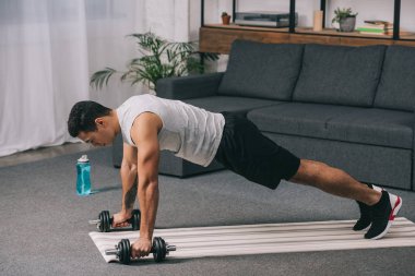 bı-ırkçı adam tahta egzersiz fitness mat oturma odasında dumbbells ile yapmak 