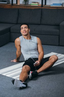bı-ırkçı adam holding smartphone ve fitness mat kulaklıklar müzik dinleme