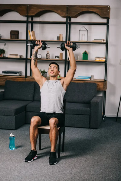 Mixed Race Athlete Holding Heavy Dumbbells Head While Sitting Chair — Stock Photo, Image