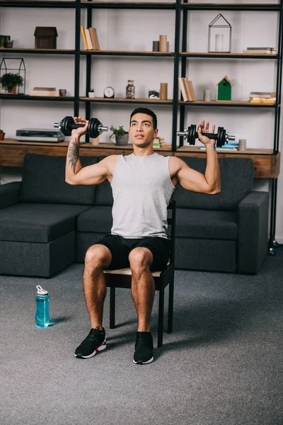 Tattooed Mixed Race Man Exercising Dumbbells Chair Home Gym — Stock Photo, Image