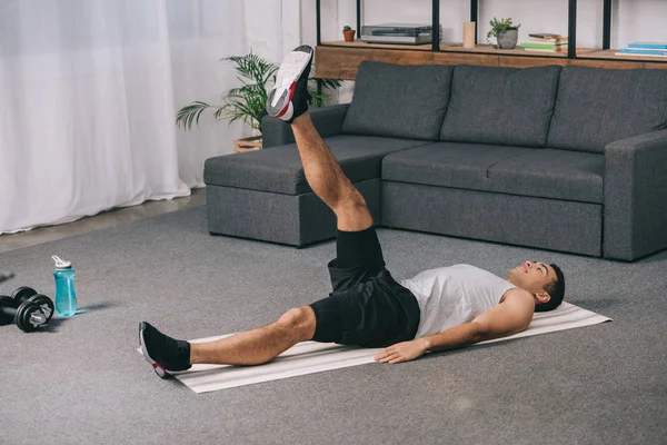 Φυλετική Αθλητής Κάνει Άσκηση Στα Πόδια Ενώ Ξαπλωμένος Γυμναστήριο Χαλί — Φωτογραφία Αρχείου
