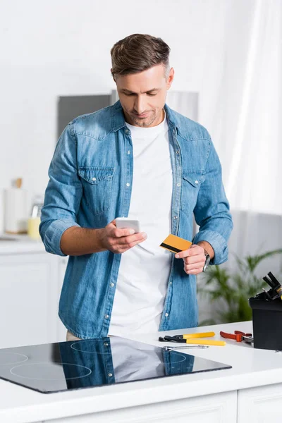 Homem Bonito Segurando Smartphone Cartão Crédito Perto Caixa Ferramentas — Fotografia de Stock