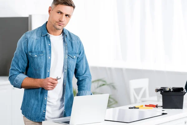Handsome Man Holding Wrench While Standing Laptop — Stock Photo, Image