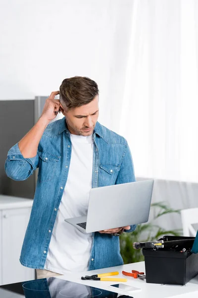 Homem Confuso Segurando Laptop Com Caixa Ferramentas Mesa Cozinha — Fotografia de Stock
