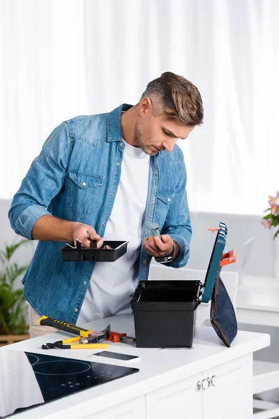 Hombre Guapo Mirando Dentro Caja Herramientas Mientras Está Pie Cocina — Foto de Stock